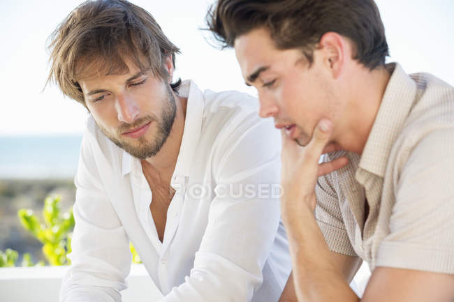 Крупный план друзей-мужчин, сидящих вместе и думающих: — стоковое фото