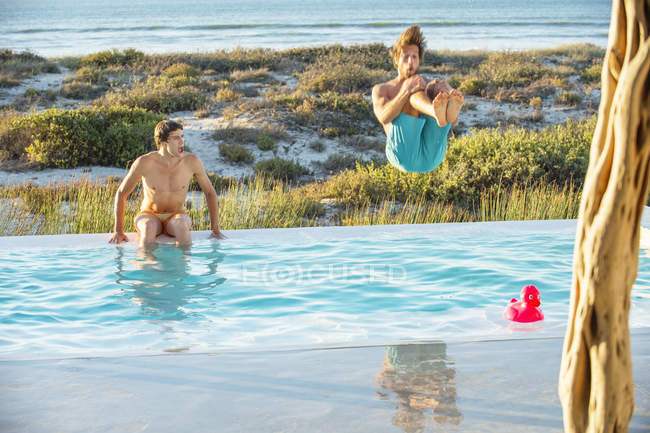 Amigos hombres disfrutando en la piscina en la playa - foto de stock