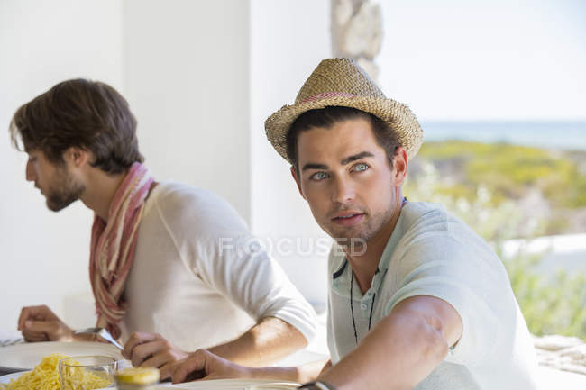 Amigos do sexo masculino sentados em uma mesa de jantar e almoçando — Fotografia de Stock