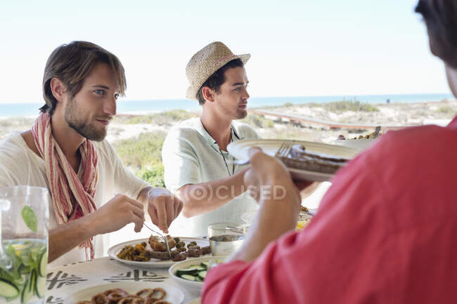 Amigos almorzando en la mesa - foto de stock
