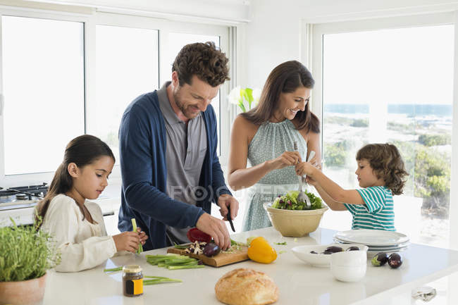 Família feliz preparando comida na casa costeira — Fotografia de Stock