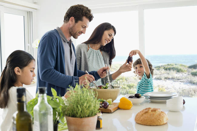 Glückliche Familie bereitet Essen im Küstenhaus zu — Stockfoto