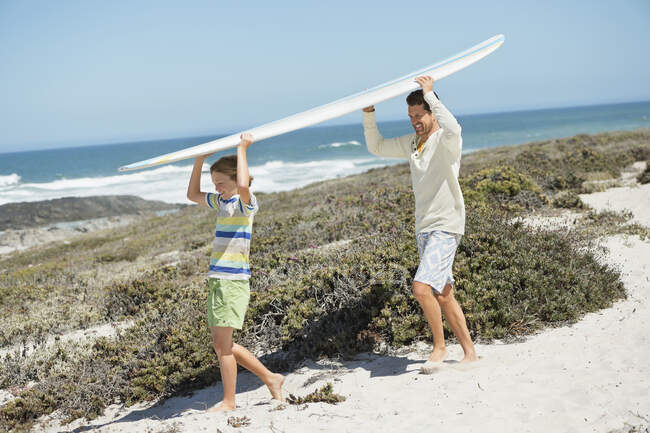 Чоловік і його син носять серфінг на пляжі. — стокове фото