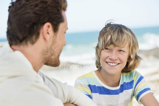 Homme assis avec son fils sur la plage — Photo de stock