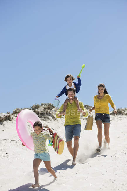 Счастливая семья гуляет по песчаному пляжу летом — стоковое фото