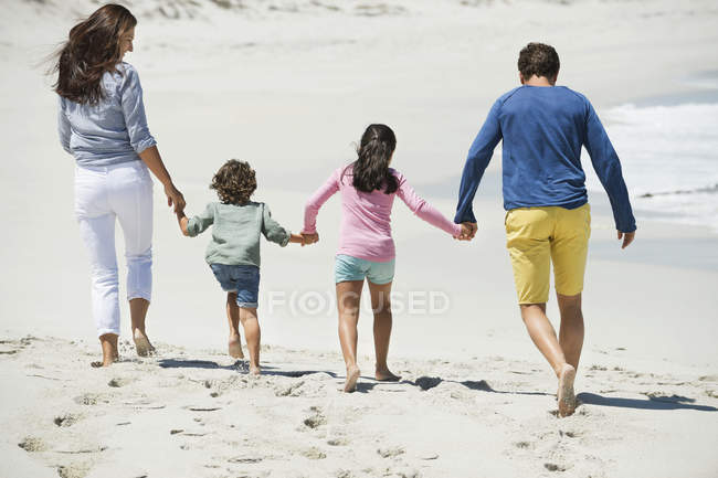 Visão traseira da família andando na praia arenosa — Fotografia de Stock