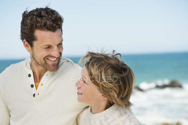Чоловік з сином посміхається на пляжі — стокове фото
