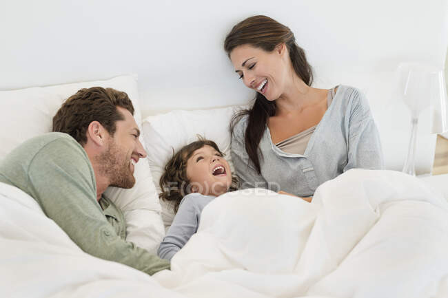Pais brincando com seu filho na cama — Fotografia de Stock