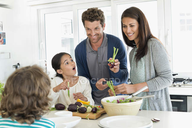 Familia feliz preparando comida en la cocina - foto de stock