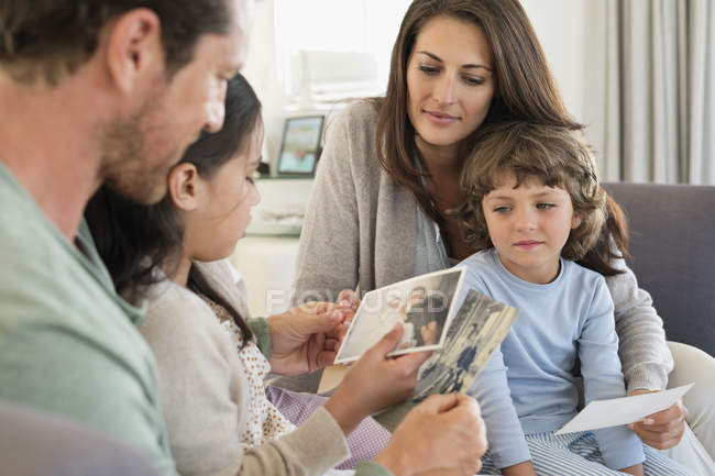 Parents showing photographs to children in living room — Stock Photo