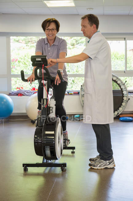 Fisioterapeuta ajudando um paciente a andar de bicicleta de exercício — Fotografia de Stock