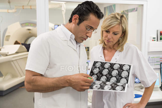 Médicos examinando informe de resonancia magnética en sala de exploración médica - foto de stock