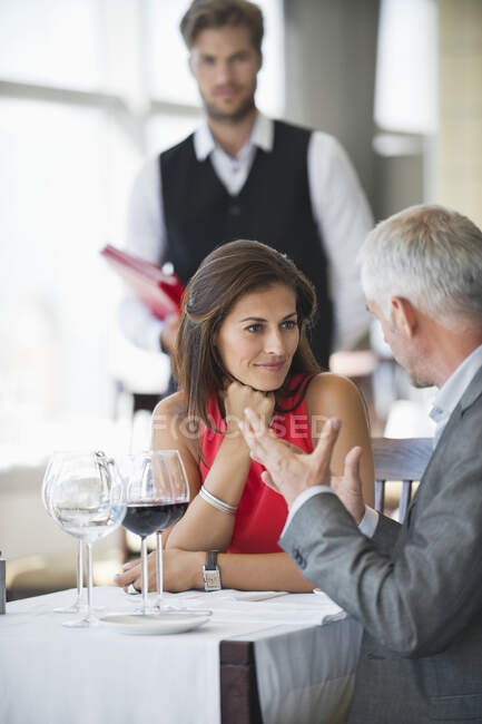 Paar diskutiert in Restaurant mit Kellner im Hintergrund — Stockfoto