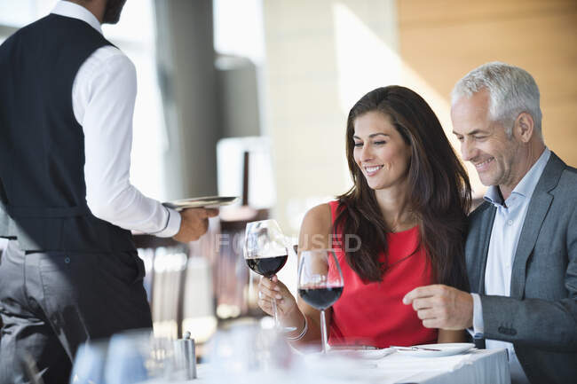Casal desfrutando de vinho tinto em um restaurante — Fotografia de Stock
