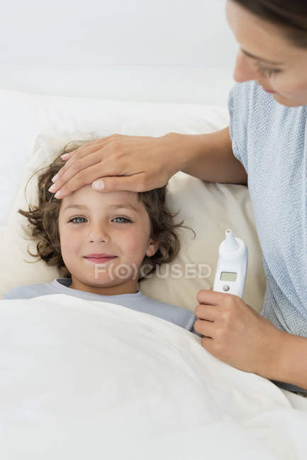 Donna che tocca la fronte del figlio che sembra malato — Foto stock