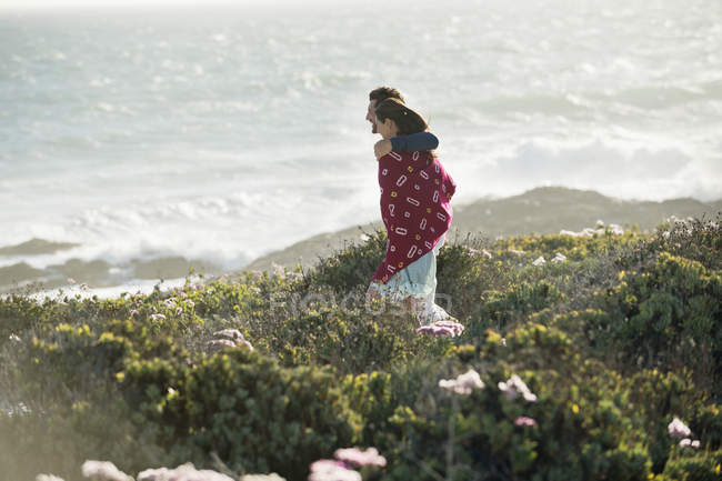 Feliz abrazo pareja caminando en la costa del mar - foto de stock