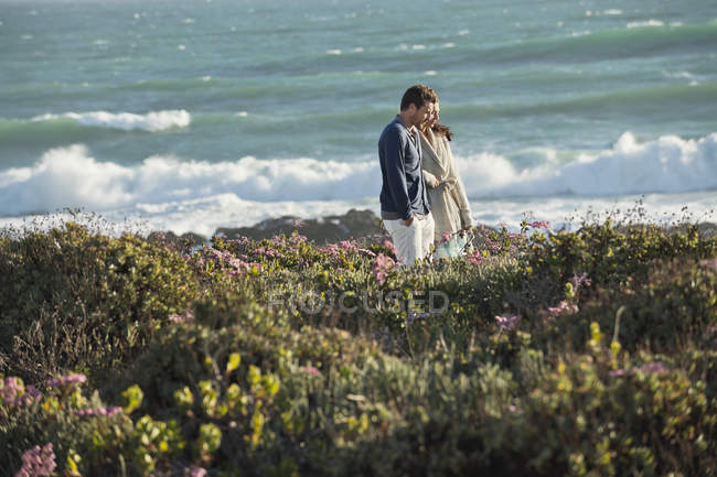 Couple marchant dans la végétation sur la côte maritime — Photo de stock