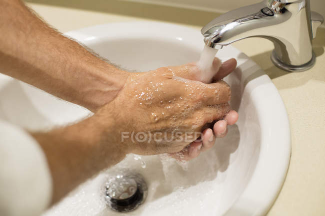 Nahaufnahme eines Mannes, der sich unter Wasserhahn die Hände wäscht — Stockfoto