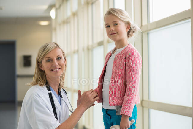 Retrato de una enfermera sonriendo con una chica - foto de stock