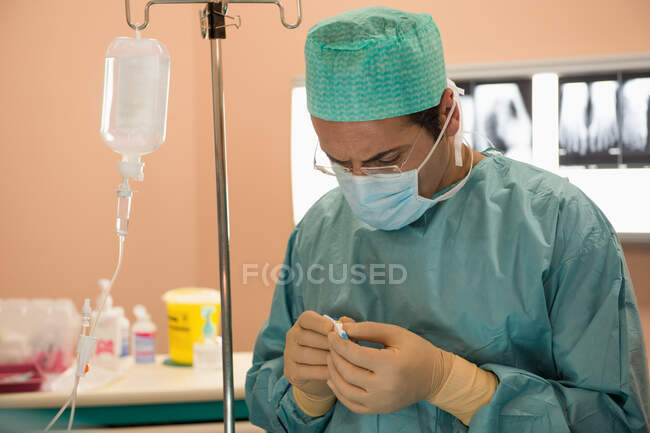Chirurgo di sesso maschile che esamina attrezzature mediche in sala operatoria — Foto stock