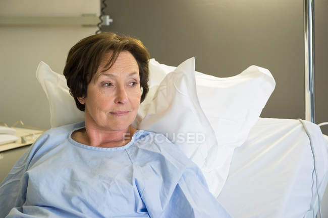 Sorridente donna matura sdraiata nel letto d'ospedale e guardando altrove — Foto stock