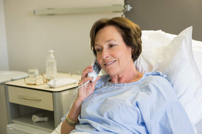Зрелая женщина разговаривает по телефону на больничной койке — стоковое фото