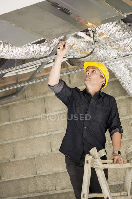 Engenheiro masculino em capacete amarelo trabalhando no local — Fotografia de Stock