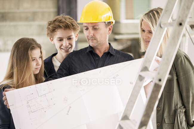 Ingeniero mostrando el plano a la familia - foto de stock