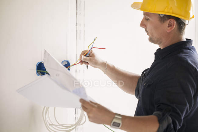 Primer plano del electricista masculino que trabaja en el lugar - foto de stock