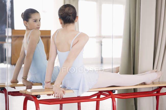 Маленькая балерина сидит перед зеркалом в танцевальной студии — стоковое фото