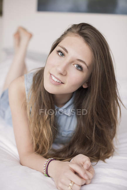 Portrait of happy teenage girl lying on bed — Stock Photo