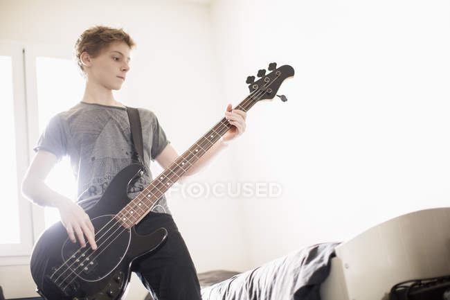 Мальчик-подросток играет на гитаре дома — стоковое фото
