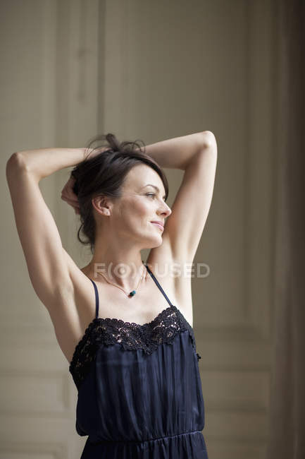 Portrait of dreamy elegant woman standing with hands in hair — Stock Photo