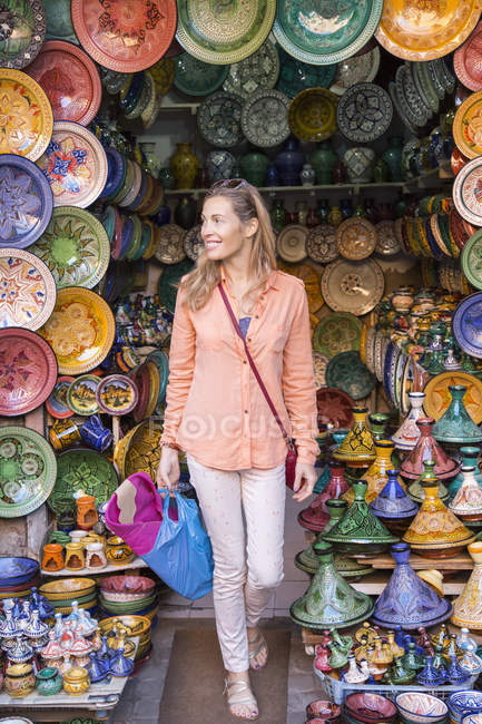 Mujer de compras en la tienda de cerámica en el zoco, Marrakech, Marruecos - foto de stock