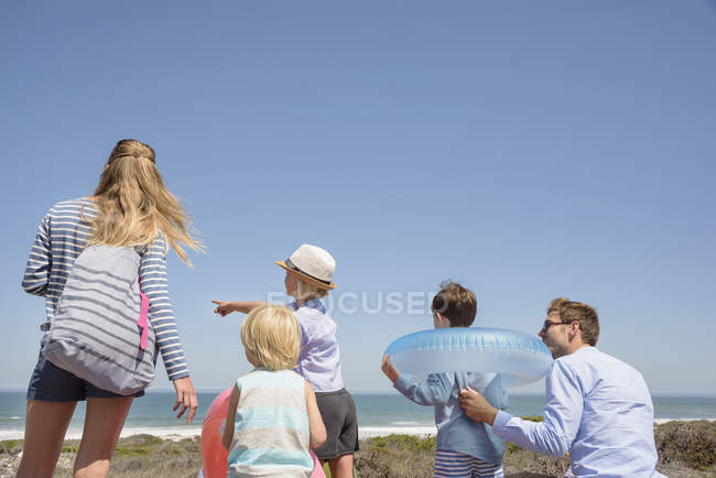 Joyeux jeune famille debout sur la plage ensoleillée — Photo de stock