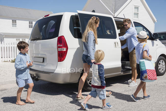 Молода сім'я сідає в машину на канікули — стокове фото