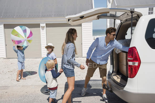 Jeune famille emballage voiture avec des engins de plage pour les vacances — Photo de stock