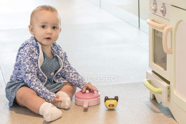 Ritratto di bambina che gioca con il giocattolo sul pavimento di casa — Foto stock