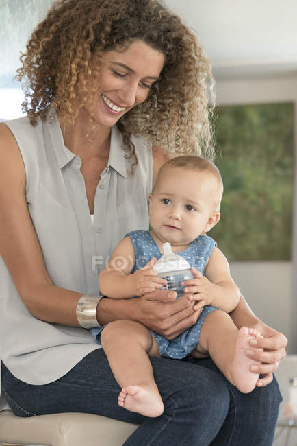 Close-up of mother and daughter sitting together and holding baby bottle — Stock Photo