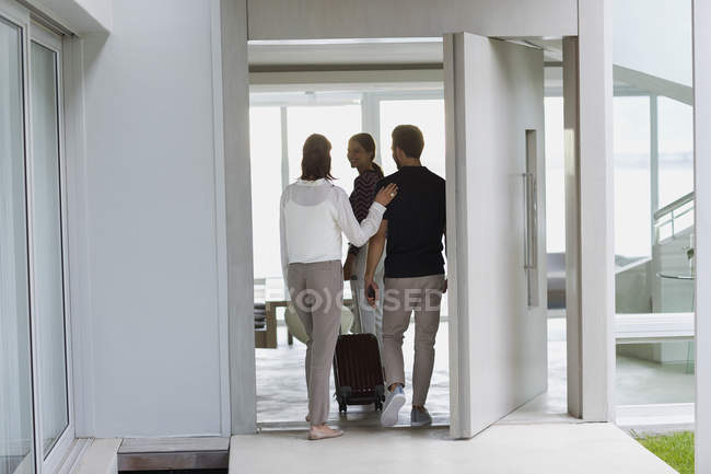 Couple with suitcase entering to friend house — Stock Photo
