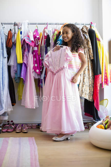 Lächelndes kleines Mädchen probiert Kleid im Zimmer an — Stockfoto