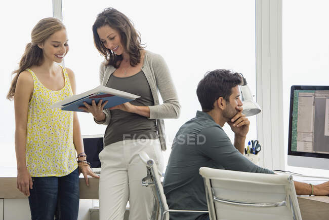 Businesswoman discussing file with her colleague with a man working on pc — Stock Photo