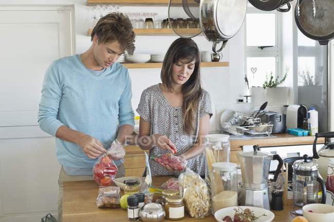 Улыбающаяся молодая пара готовит на кухне — стоковое фото