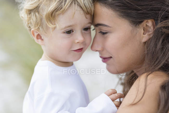 Nahaufnahme einer lächelnden Frau, die ihren kleinen Sohn im Freien hält — Stockfoto