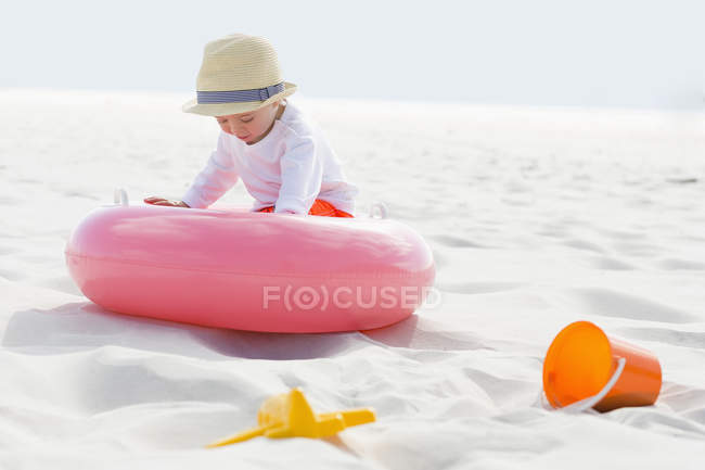 Menino de chapéu de palha brincando na praia de areia — Fotografia de Stock
