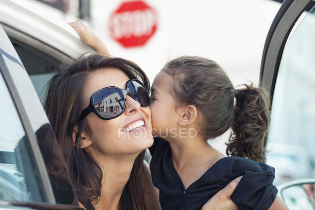 Elegante jovem mulher com bonito filhinha beijando no carro — Fotografia de Stock