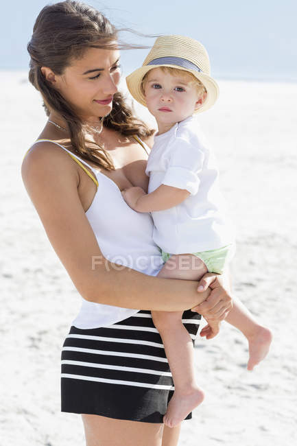Glückliche Frau trägt Baby-Sohn am Strand — Stockfoto