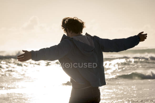 Happy young man with arm outstretched on beach — Stock Photo