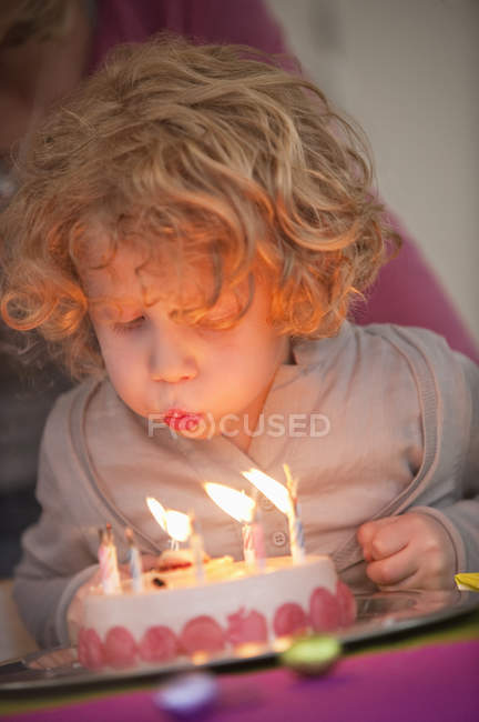 Junge pustet Kerzen auf Geburtstagstorte aus — Stockfoto