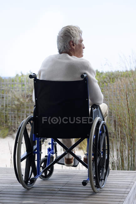 Старший человек в инвалидной коляске расслабляется на открытом воздухе — стоковое фото